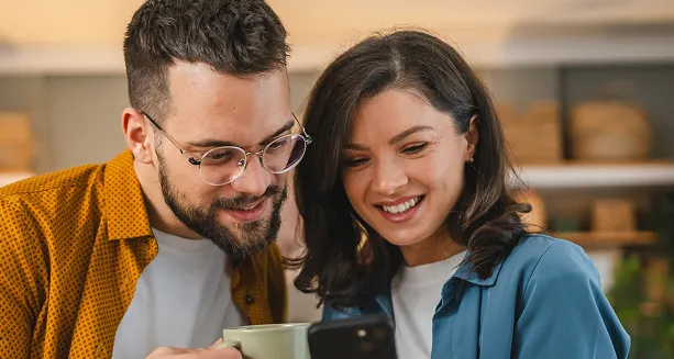 Pareja sonriente mirando un celular, informándose sobre la integración entre BICECORP y Grupo Security